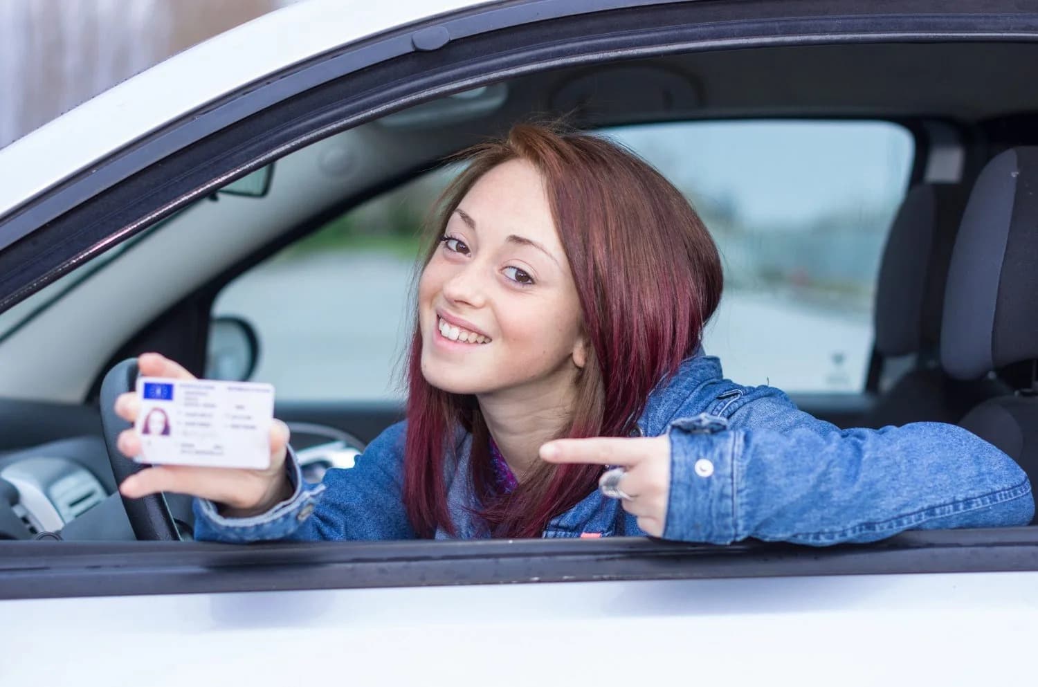 Jeune conductrice montrant son permis de conduire obtenu après une formation accélérée
